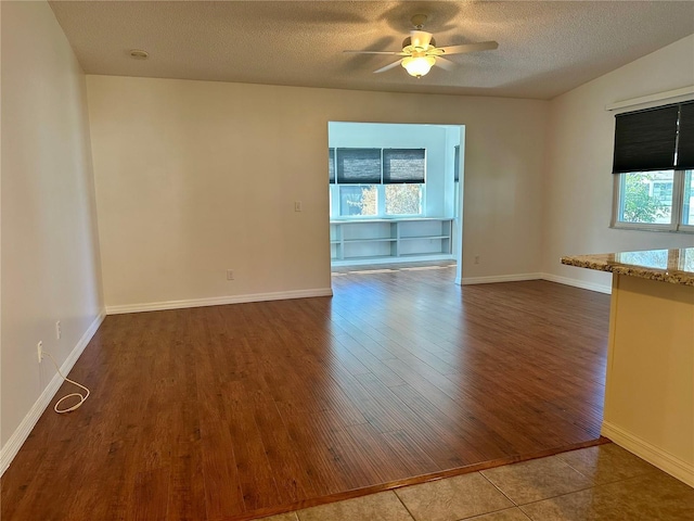 unfurnished room featuring ceiling fan, dark hardwood / wood-style flooring, and a textured ceiling