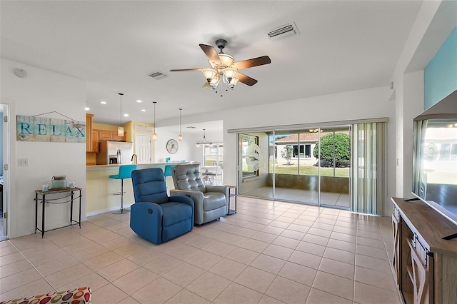 tiled living room featuring ceiling fan with notable chandelier