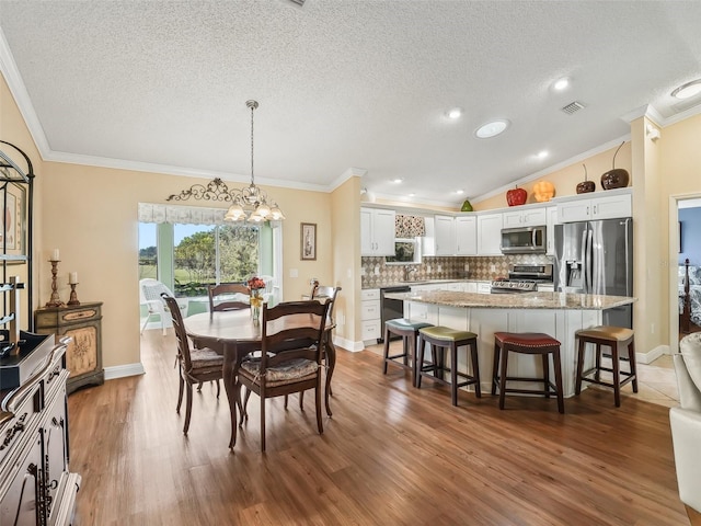 dining space featuring hardwood / wood-style floors, a textured ceiling, vaulted ceiling, and crown molding