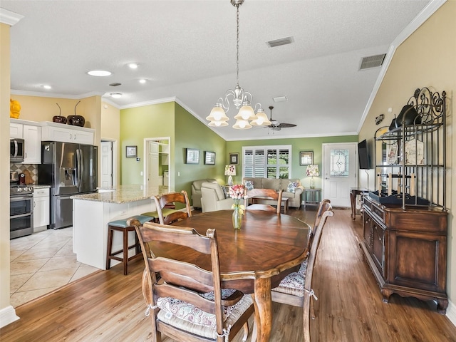 dining room with a textured ceiling, ceiling fan with notable chandelier, light wood-type flooring, and ornamental molding