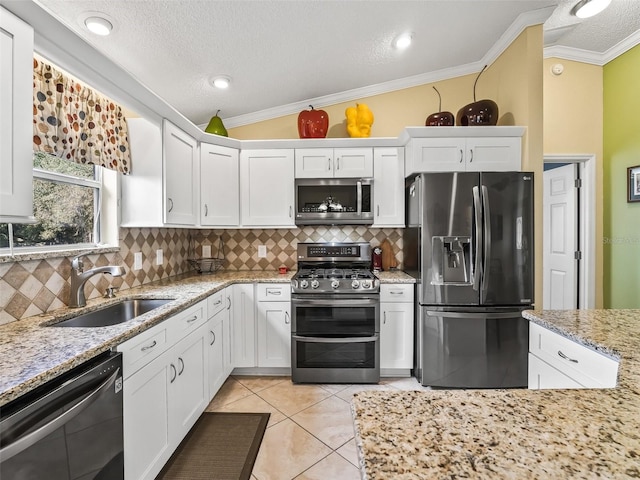 kitchen with lofted ceiling, sink, ornamental molding, white cabinetry, and stainless steel appliances