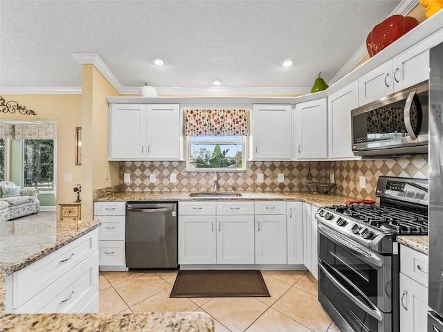 kitchen with white cabinetry, sink, stainless steel appliances, light tile patterned floors, and ornamental molding