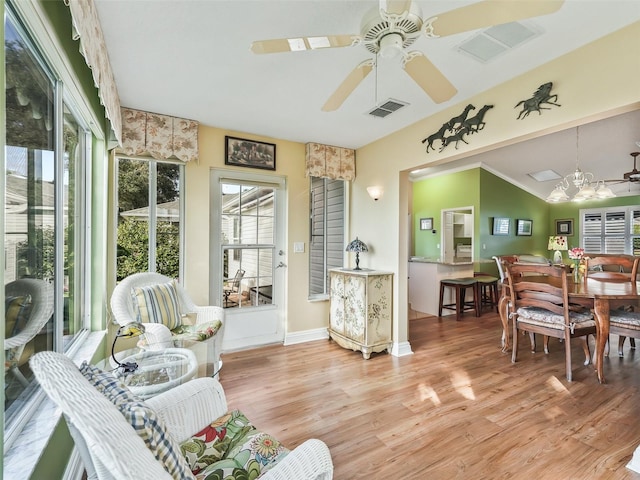 sunroom featuring ceiling fan with notable chandelier and vaulted ceiling