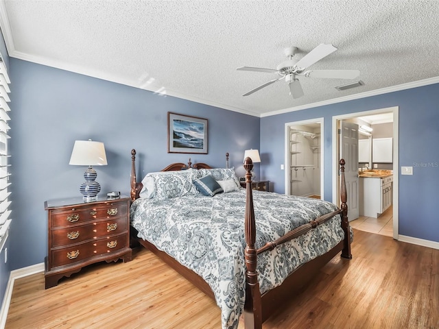 bedroom with a walk in closet, ceiling fan, a textured ceiling, light hardwood / wood-style floors, and a closet