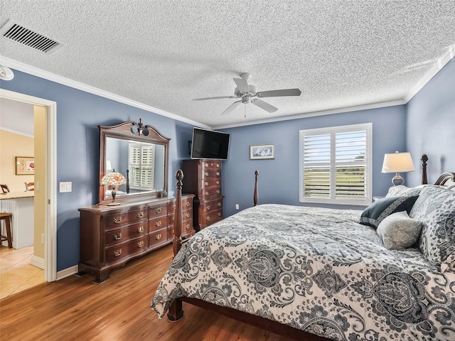 bedroom with ceiling fan, crown molding, a textured ceiling, and light wood-type flooring