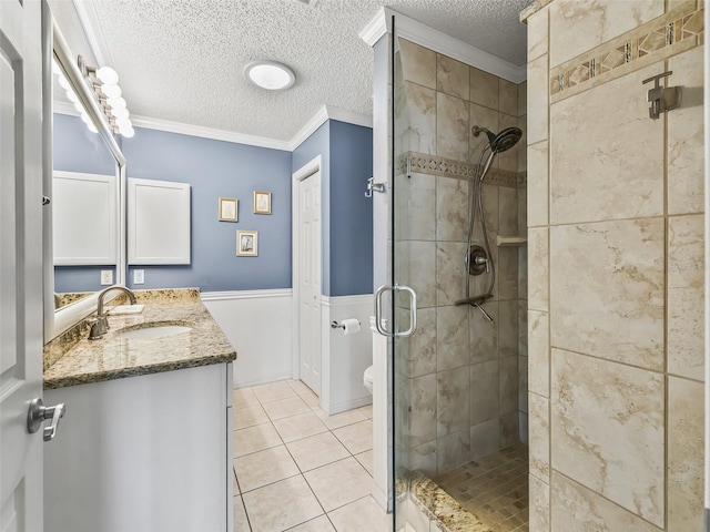 bathroom featuring tile patterned floors, an enclosed shower, a textured ceiling, vanity, and ornamental molding