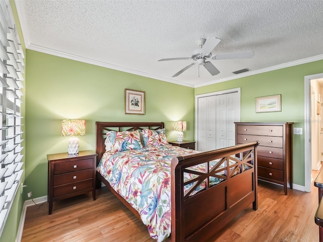 bedroom featuring ceiling fan, crown molding, a textured ceiling, a closet, and light wood-type flooring