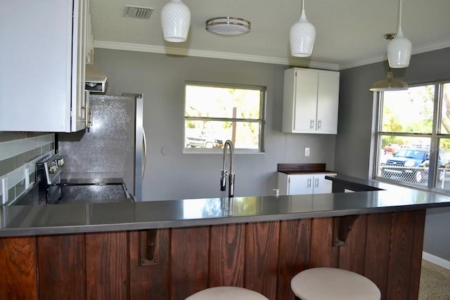 kitchen featuring white cabinets, backsplash, stove, and hanging light fixtures