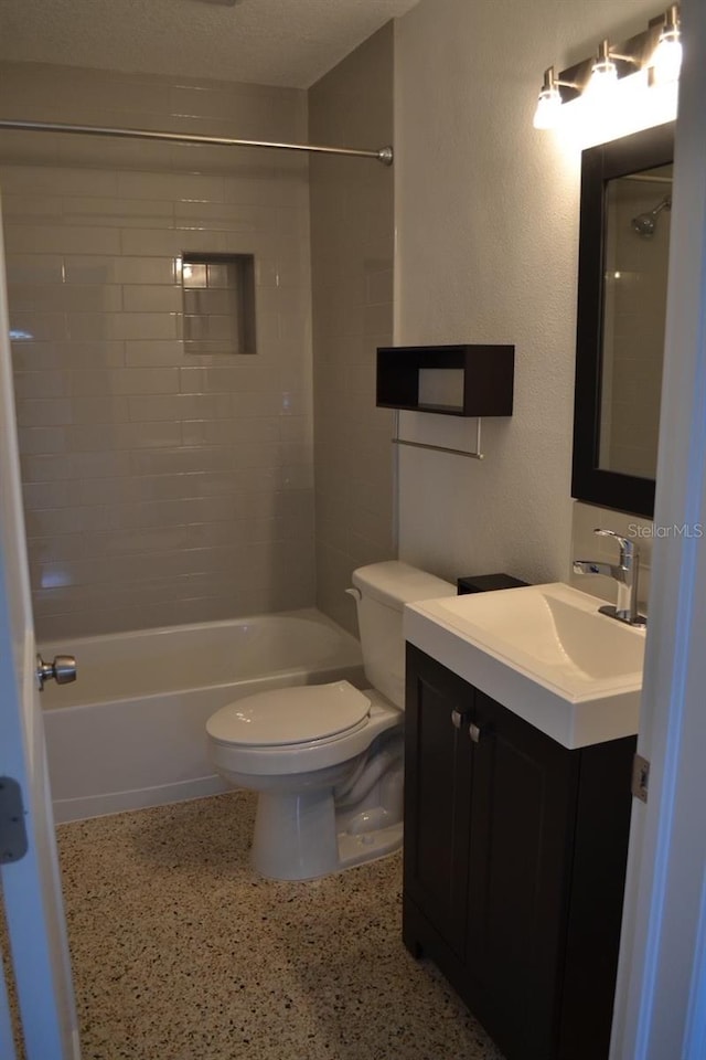 full bathroom featuring vanity, toilet, a textured ceiling, and tiled shower / bath