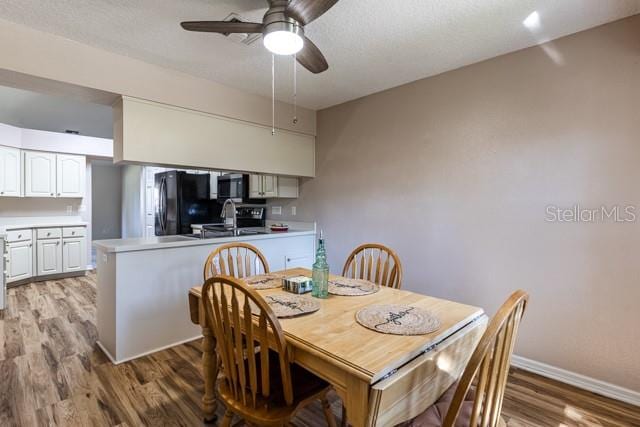 dining space featuring ceiling fan, sink, and light hardwood / wood-style flooring