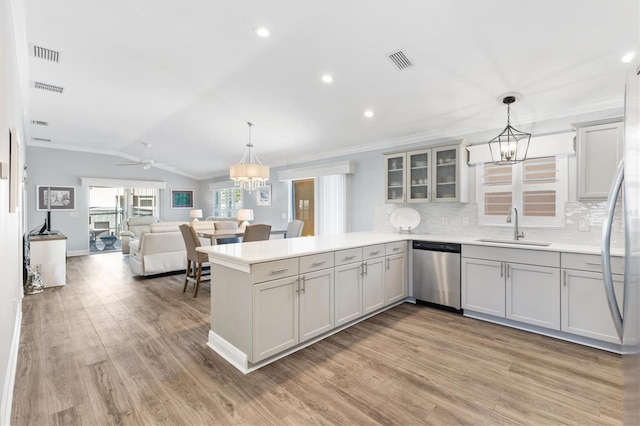 kitchen featuring dishwasher, sink, hanging light fixtures, light hardwood / wood-style floors, and kitchen peninsula