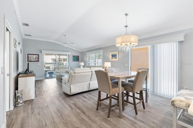 dining space featuring light hardwood / wood-style flooring, ceiling fan with notable chandelier, lofted ceiling, and ornamental molding