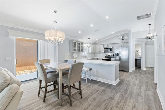 dining space with light hardwood / wood-style floors, ornamental molding, sink, and vaulted ceiling