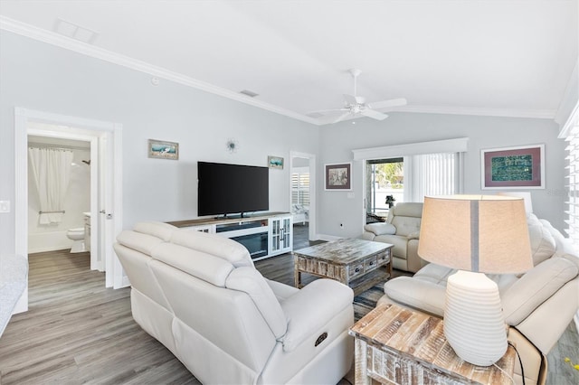 living room with ceiling fan, light wood-type flooring, ornamental molding, and vaulted ceiling