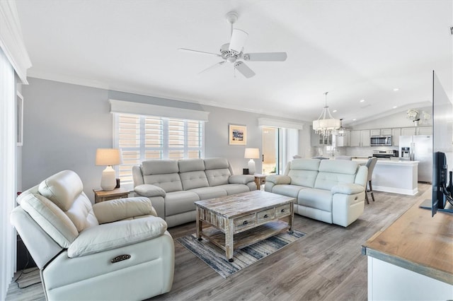 living room with ceiling fan with notable chandelier, light hardwood / wood-style floors, vaulted ceiling, and ornamental molding