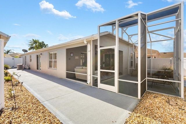 rear view of house with cooling unit, a lanai, and a patio