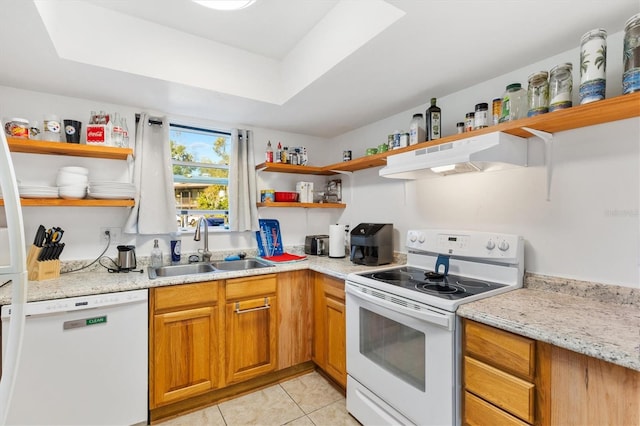 kitchen featuring light stone counters, white appliances, a raised ceiling, sink, and light tile patterned floors