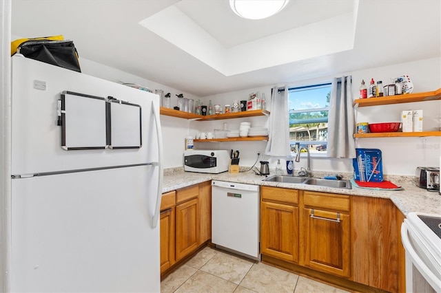 kitchen featuring white appliances, sink, light stone countertops, light tile patterned floors, and a tray ceiling