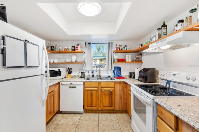 kitchen featuring light stone countertops, white appliances, a raised ceiling, sink, and light tile patterned flooring