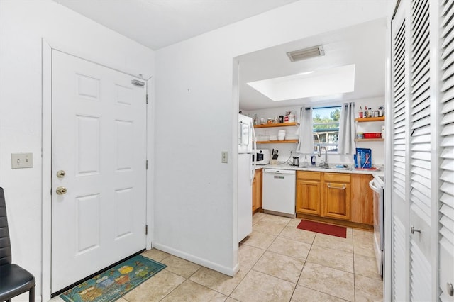 kitchen with sink, light tile patterned floors, and white appliances