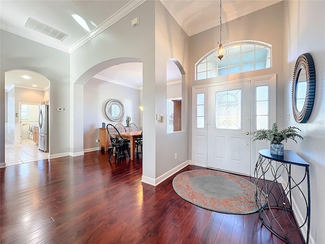 foyer entrance featuring dark hardwood / wood-style floors, crown molding, and a high ceiling