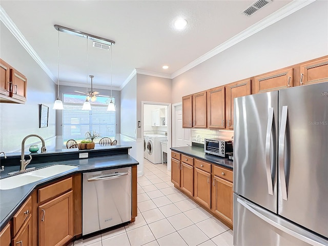 kitchen featuring washer and clothes dryer, sink, hanging light fixtures, ornamental molding, and stainless steel appliances