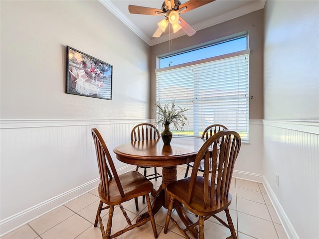 tiled dining room with ceiling fan and ornamental molding