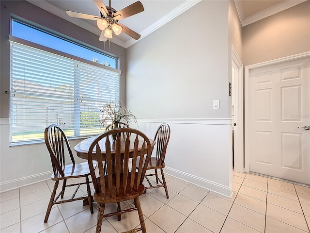 tiled dining area with ceiling fan and ornamental molding