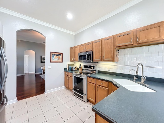 kitchen featuring appliances with stainless steel finishes, tasteful backsplash, crown molding, sink, and light tile patterned floors