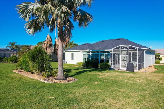 back of property featuring a lanai and a lawn