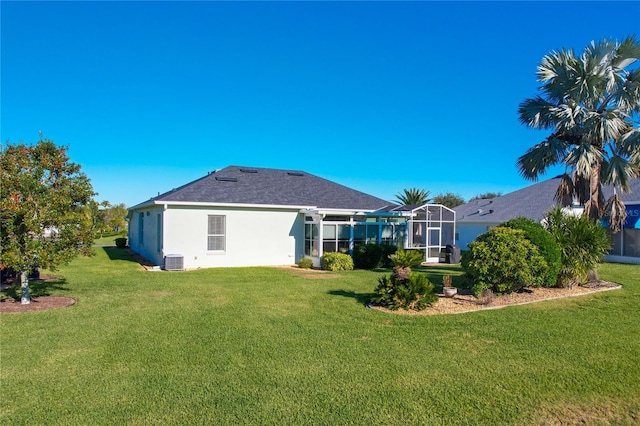 rear view of house with a yard, central AC, and a lanai