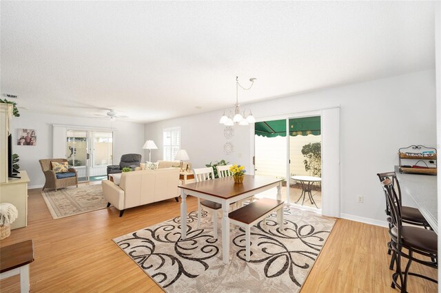 dining room with ceiling fan with notable chandelier and light hardwood / wood-style flooring