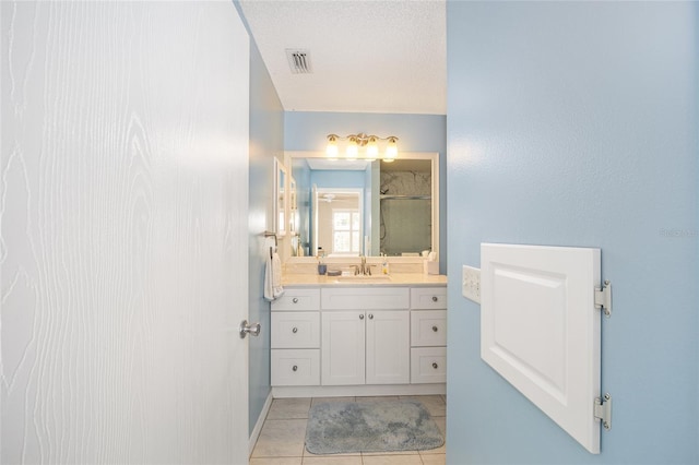 bathroom with tile patterned floors, vanity, an enclosed shower, and a textured ceiling