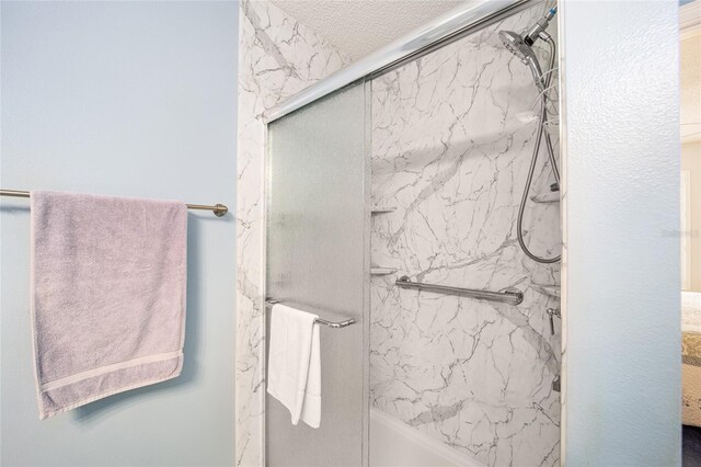 bathroom with a textured ceiling and bath / shower combo with glass door