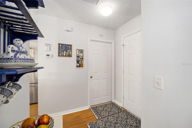 foyer entrance featuring a textured ceiling and light hardwood / wood-style floors