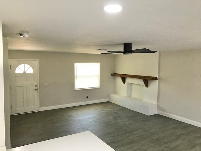 unfurnished living room featuring ceiling fan, a healthy amount of sunlight, and dark hardwood / wood-style flooring