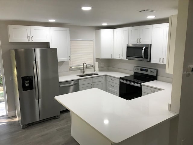 kitchen featuring kitchen peninsula, sink, white cabinets, and stainless steel appliances