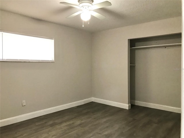 unfurnished bedroom featuring ceiling fan, dark hardwood / wood-style flooring, and a closet