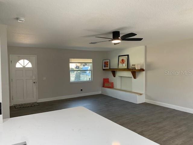 foyer with baseboards, a ceiling fan, dark wood-style flooring, and a textured ceiling