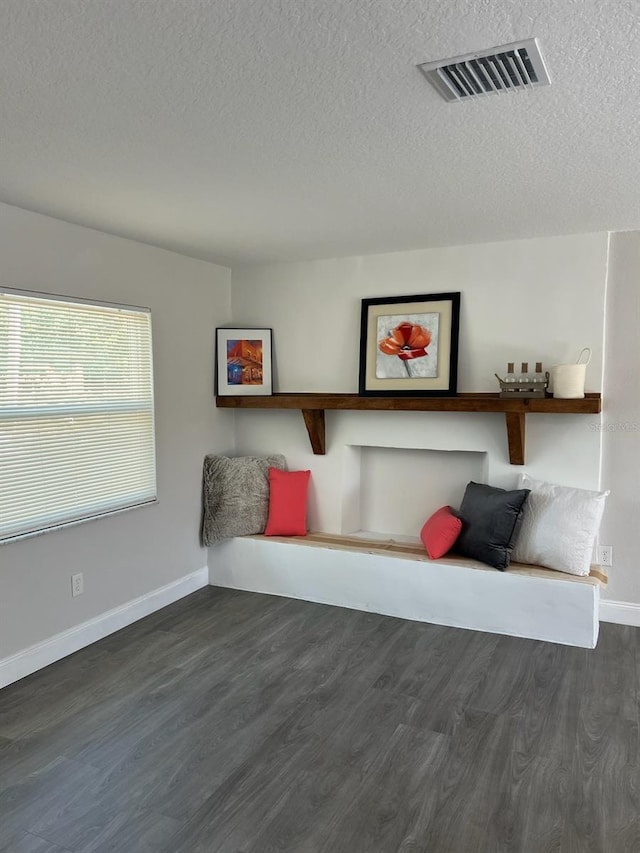 unfurnished room with visible vents, a textured ceiling, dark wood-type flooring, and baseboards