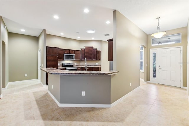 kitchen featuring light stone countertops, sink, stainless steel appliances, and decorative light fixtures