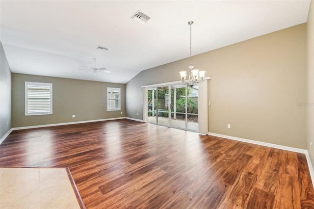 spare room featuring ceiling fan with notable chandelier, hardwood / wood-style flooring, and vaulted ceiling