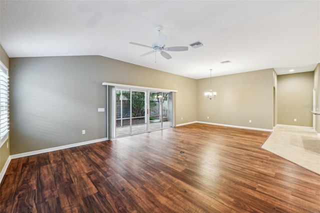 empty room with hardwood / wood-style floors, ceiling fan with notable chandelier, and lofted ceiling