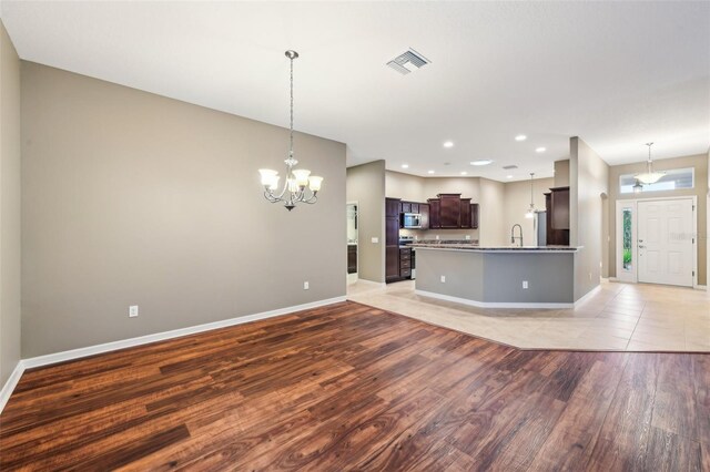 kitchen featuring decorative light fixtures, dark brown cabinetry, light hardwood / wood-style floors, and stainless steel appliances