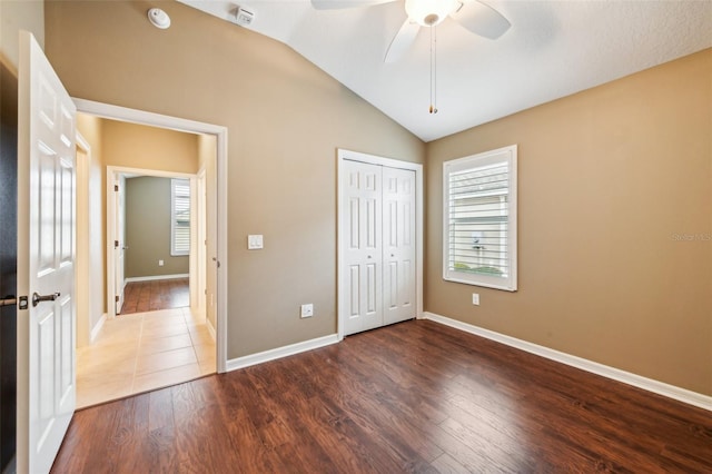 unfurnished bedroom with ceiling fan, a closet, lofted ceiling, and hardwood / wood-style flooring