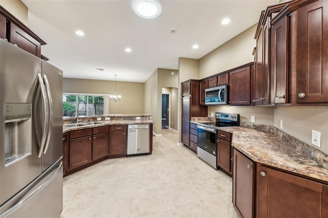 kitchen with light stone countertops, stainless steel appliances, sink, decorative light fixtures, and a notable chandelier