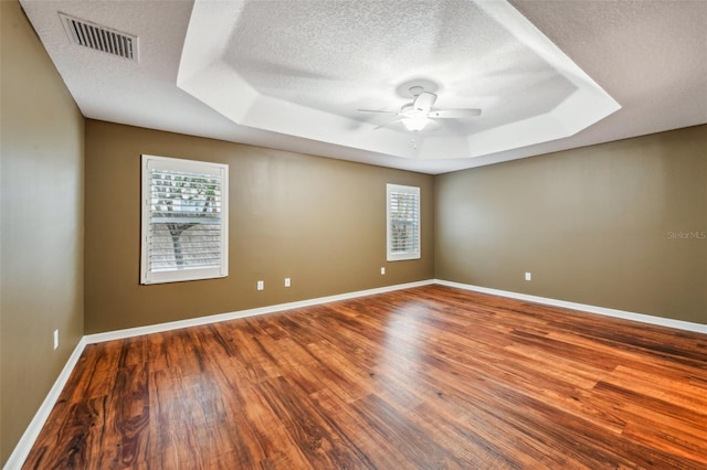 spare room featuring wood-type flooring, a textured ceiling, a raised ceiling, and ceiling fan