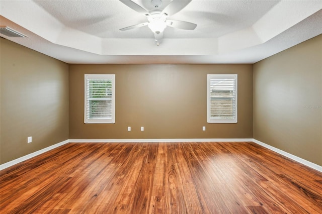 unfurnished room featuring hardwood / wood-style floors, a raised ceiling, and a wealth of natural light