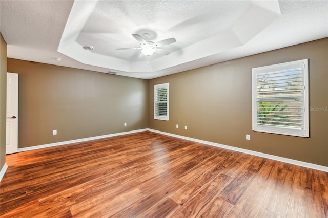 unfurnished room with wood-type flooring, a textured ceiling, and a raised ceiling