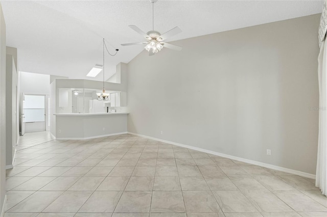 unfurnished living room featuring ceiling fan with notable chandelier, a skylight, high vaulted ceiling, and light tile patterned flooring